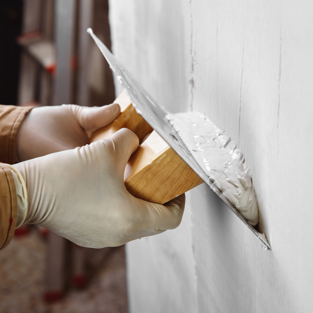 maçon qui fait de l'enduit sur un mur